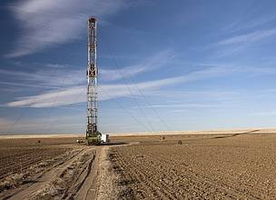 A fracking rig drills in a field in a farm plot.